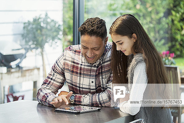 Vater und Tochter benutzen ein digitales Tablet in der Küche
