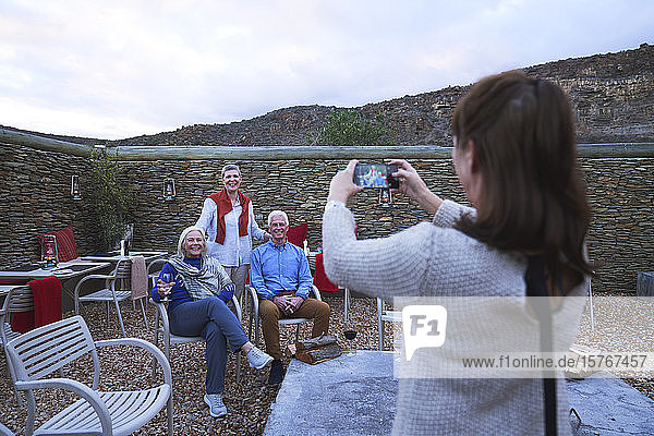 Frau mit Fotohandy fotografiert ältere Freunde auf der Veranda
