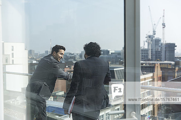 Geschäftsleute unterhalten sich auf einem sonnigen  städtischen Balkon