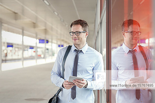 Geschäftsmann mit digitalem Tablet wartet in der Nähe des Bahnsteigs