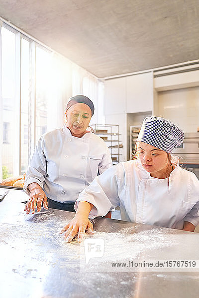 Bäckereilehrer und junge Schülerin mit Down-Syndrom  Mehlfläche