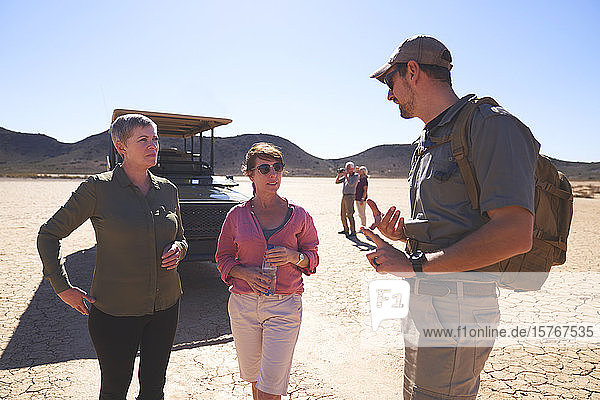Safari-Reiseleiter im Gespräch mit Frauen in der sonnigen Wüste Südafrikas