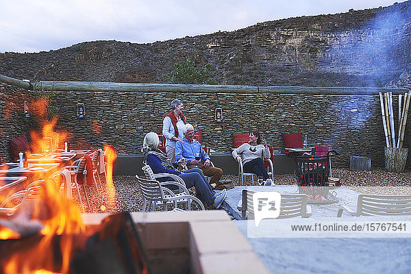 Ältere Freunde entspannen sich bei Rotwein auf der Hotelterrasse mit Feuerstelle