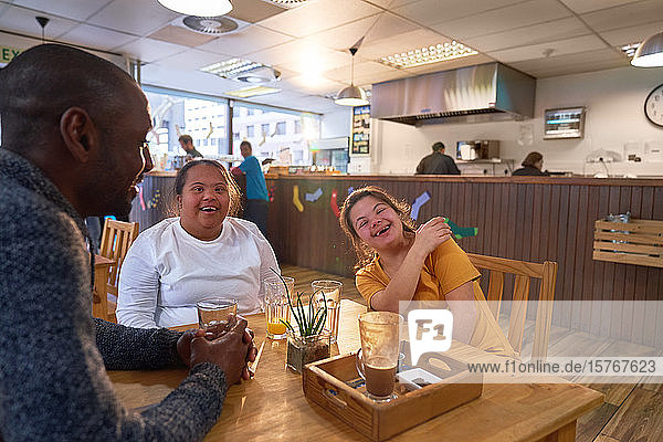 Fröhliche junge Freundinnen mit Down-Syndrom lachen im Café