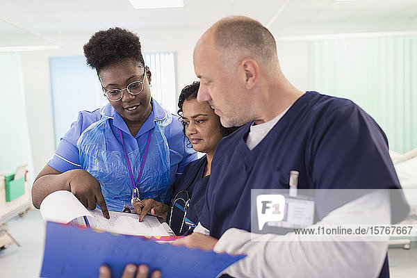 Ärzte und Krankenschwester mit Krankenblatt bei der Visite  Beratung im Krankenhauszimmer