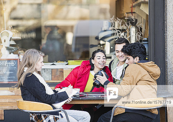 Junge erwachsene Studenten mit Digitalkamera in einem Straßencafé