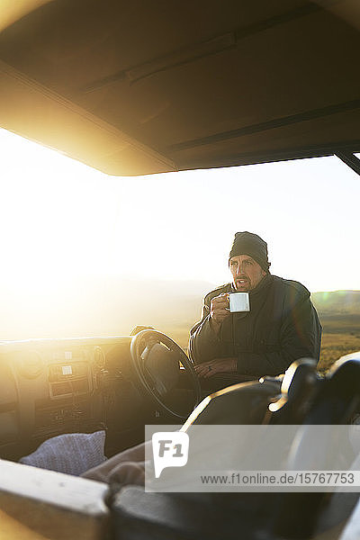 Safari-Führer trinkt Tee im Geländewagen bei Sonnenaufgang