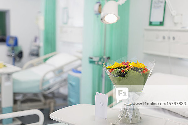 Blumenstrauß und Grußkarte auf einem Tablett in einem leeren Krankenhauszimmer