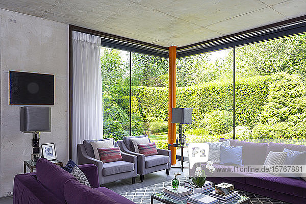 Modernes Wohnzimmer mit lila Möbeln und Blick auf den sonnigen Garten