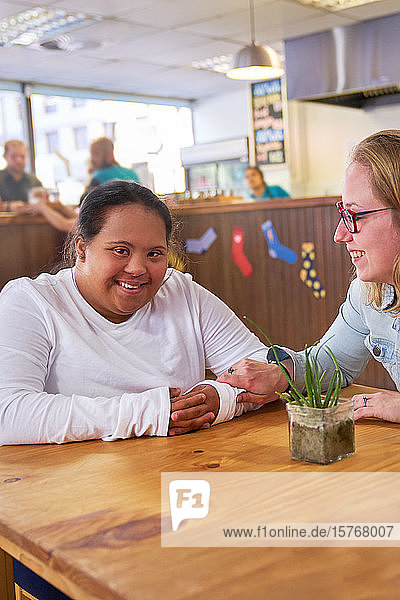 Porträt einer glücklichen jungen Frau mit Down-Syndrom in einem Café