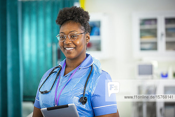 Portrait confident female nurse with digital tablet in hospital