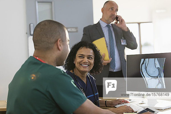 Lächelnde Krankenschwestern besprechen digitale Röntgenbilder am Computer in der Klinik