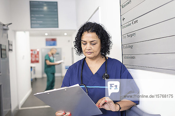 Ärztin mit Krankenblatt bei der Visite im Krankenhauskorridor