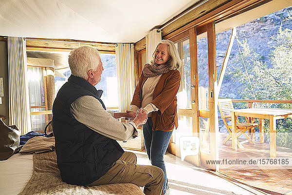 Glückliches älteres Paar  das sich im Hotelzimmer einer Safari-Lodge an den Händen hält