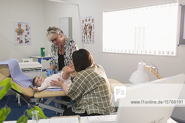Female pediatrician examining baby girl on examination room table