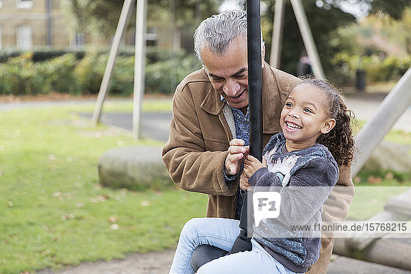Happy grandfather and granddaughter playing at playground