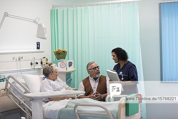 Arzt mit Krankenblatt bei der Visite  Gespräch mit älterem Ehepaar im Krankenhauszimmer