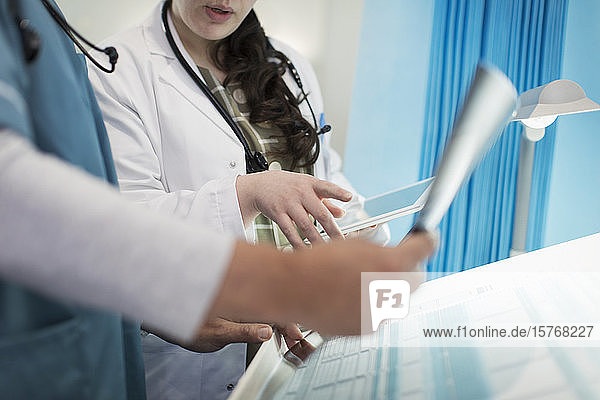 Ärzte mit digitalem Tablet bei der Besprechung von Röntgenaufnahmen in einem Krankenhauszimmer