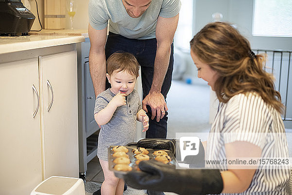 Neugieriges Kleinkind Mädchen beobachtet Mutter backen Muffins in der Küche
