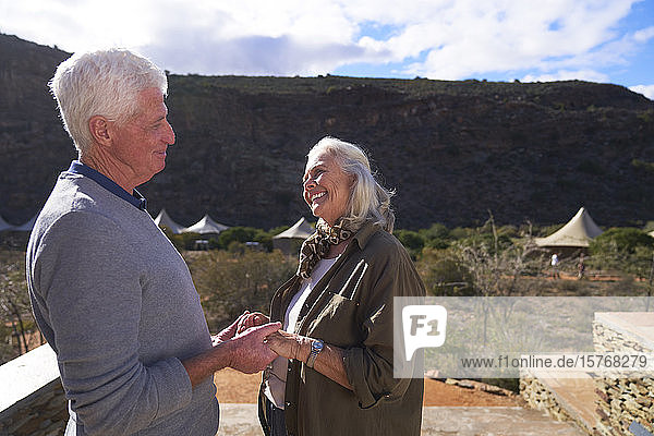 Happy senior couple on sunny safari lodge balcony South Africa