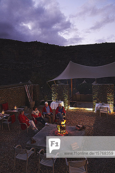 Senior friends relaxing at fire pit on hotel patio