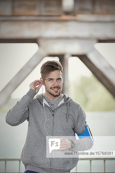 Porträt selbstbewusster junger männlicher Läufer mit Kopfhörern und mp3-Player-Armband