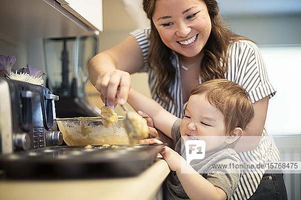 Glückliche Mutter und Kleinkind Tochter backen Muffins in der Küche