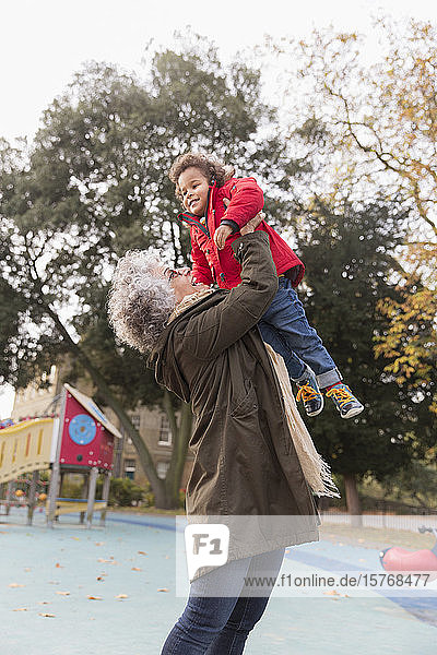Großmutter hebt ihre Enkelin auf dem Spielplatz hoch