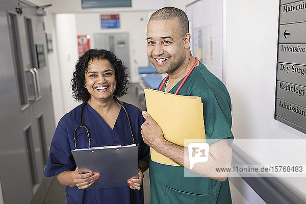 Porträt selbstbewusster Ärzte mit Krankenblatt bei der Visite im Krankenhauskorridor