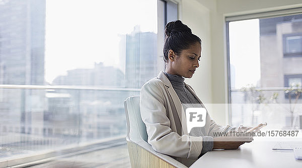 Businesswoman using smart phone in urban conference room