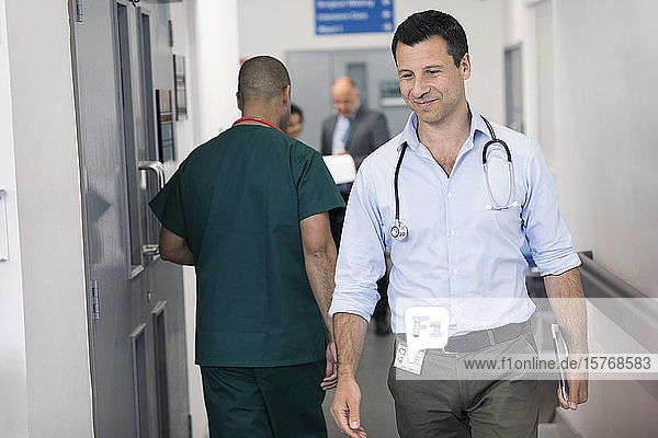 Männlicher Arzt mit digitalem Tablet im Krankenhauskorridor