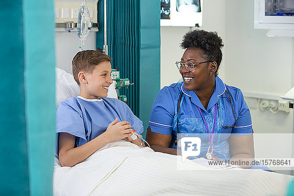 Female nurse talking with boy patient in hospital room