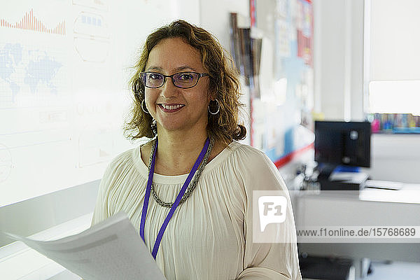 Porträt einer selbstbewussten Lehrerin vor einer Projektionsfläche im Klassenzimmer