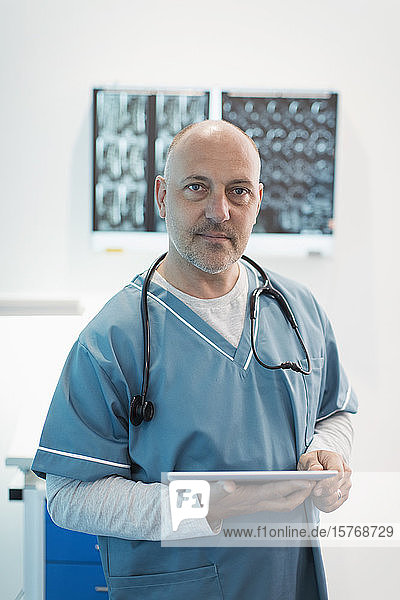 Portrait confident male doctor using digital tablet in hospital