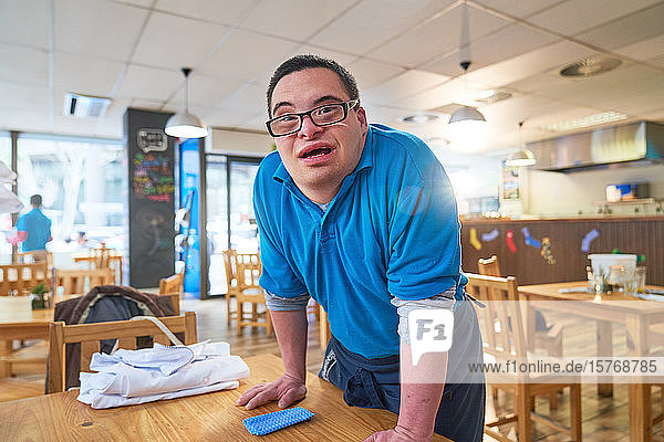 Portrait confident young man with Down Syndrome working in cafe