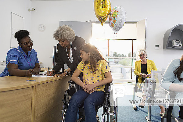 Patientin im Rollstuhl beim Einchecken am Empfang der Klinik
