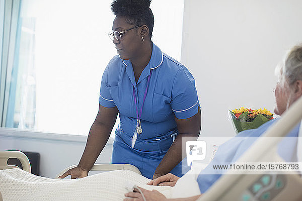 Krankenschwester hilft Patientin im Krankenhausbett