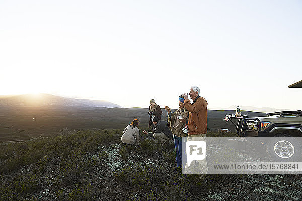 Safari-Gruppe trinkt Tee und genießt den Blick auf die Landschaft bei Sonnenaufgang