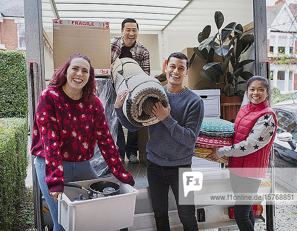 Porträt glücklicher Freunde beim Entladen eines Umzugswagens in der Einfahrt
