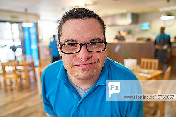 Close up portrait smiling young man with Down Syndrome in cafe