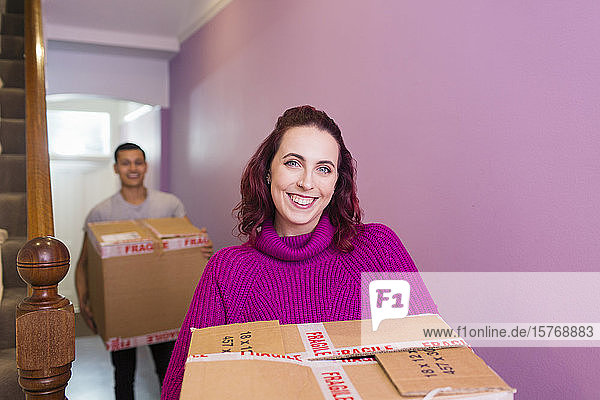 Porträt eines glücklichen Paares  das umzieht und Kartons in den Korridor trägt