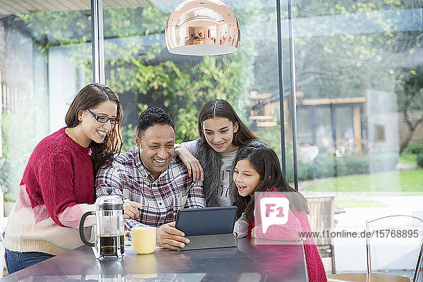 Glückliche Familie mit digitalem Tablet am Küchentisch