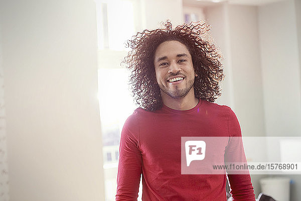 Porträt eines selbstbewussten  lächelnden jungen Mannes mit lockigem Haar