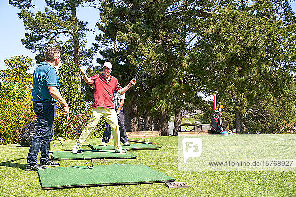 Glücklicher älterer männlicher Golfer  der auf einem sonnigen Golfplatz jubelt