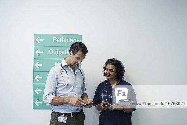 Ärzte mit Smartphones im Gespräch auf dem Krankenhausflur
