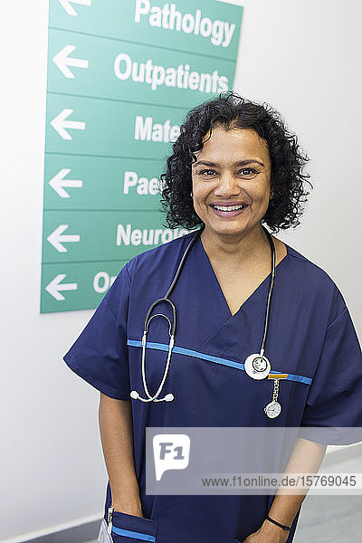 Porträt einer selbstbewussten  fröhlichen Ärztin im Krankenhausflur