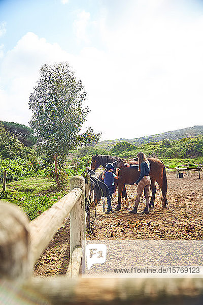 Female instructor teaching horseback riding to girl in sunny paddock