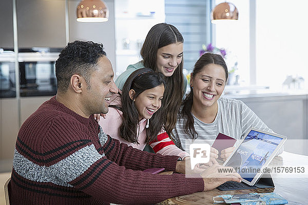 Glückliche Familie bei der Urlaubsplanung am digitalen Tablet in der Küche