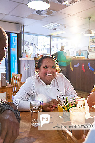 Porträt einer glücklichen jungen Frau mit Down-Syndrom in einem Café mit Freunden