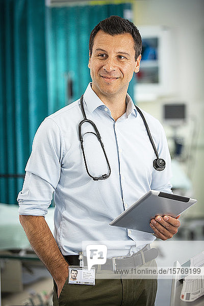 Porträt eines selbstbewussten männlichen Arztes  der ein digitales Tablet im Krankenhaus benutzt